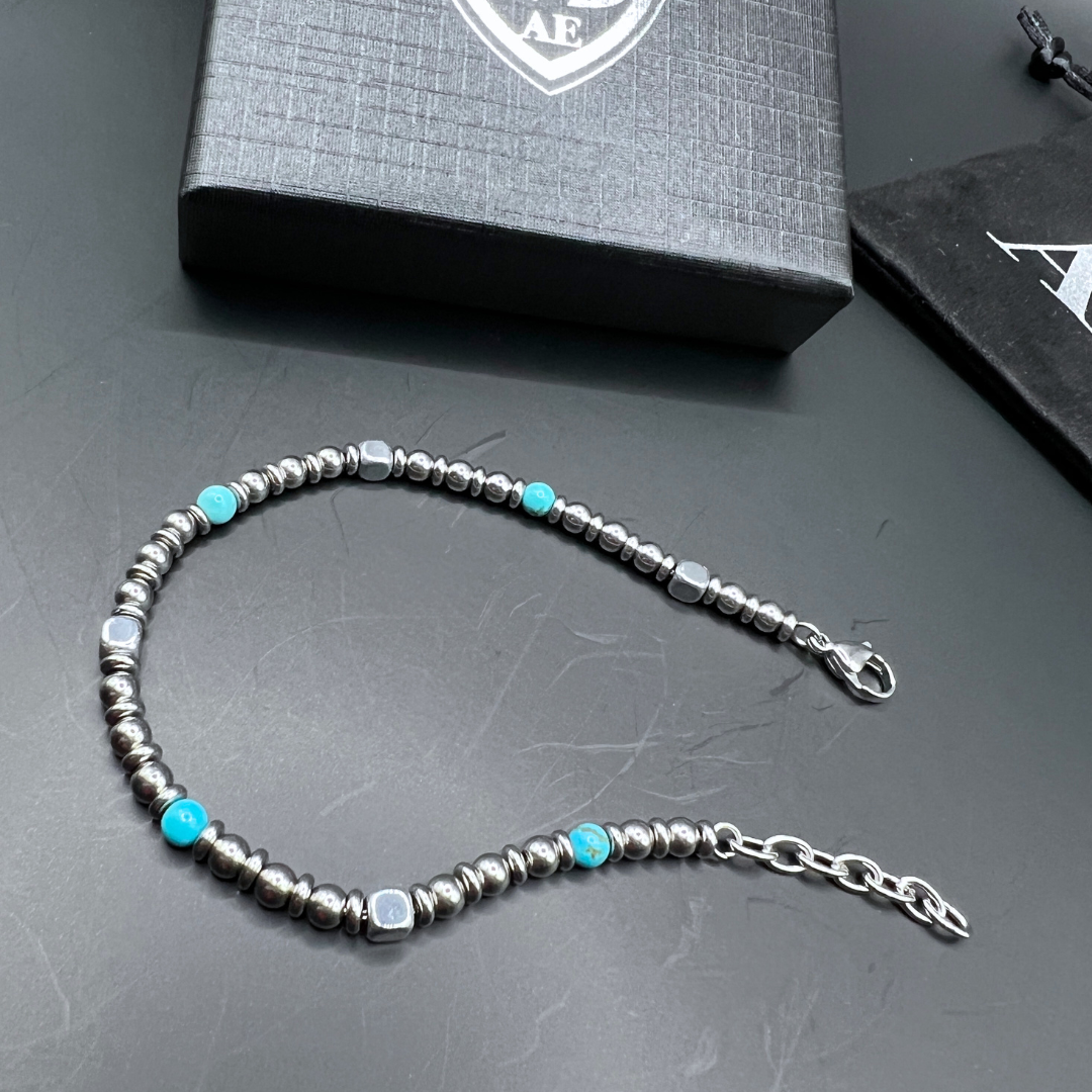 Aqua Pulse bracelet laid flat in a loop with Armoured Elegance gift box and pouch in the background