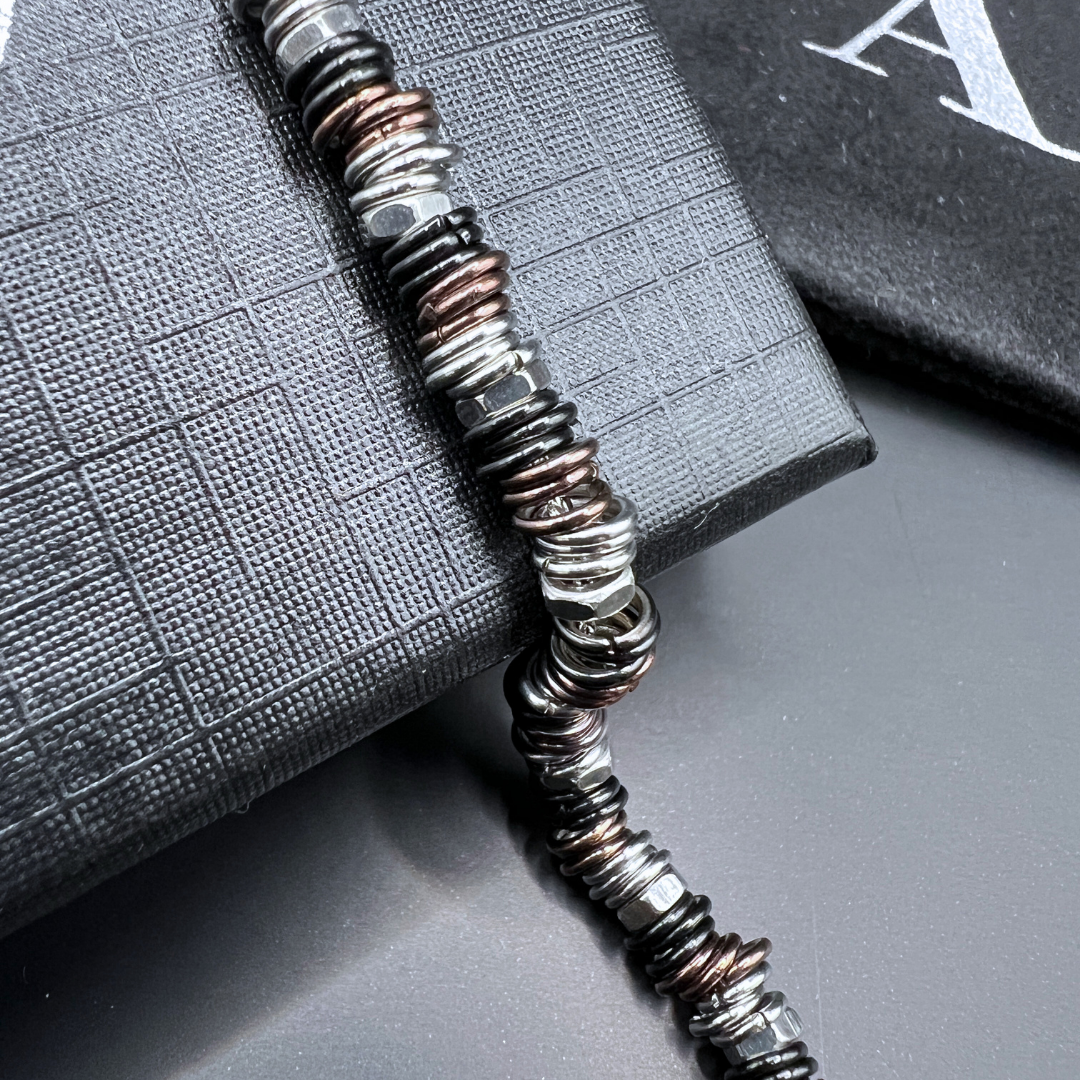 Detailed macro view of the Industrial Torque bracelet's anodised copper and black ringlets on textured box