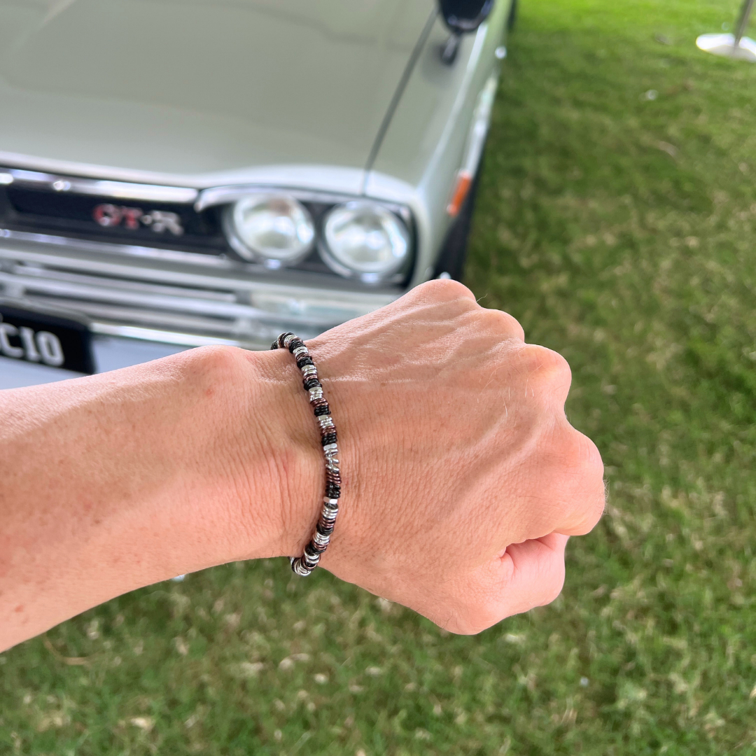 Industrial Torque bracelet variant photographed with hand in front of vintage Nissan GTR car