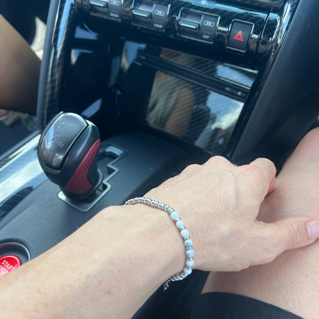 Wearing the Pure Luxe white stone bracelet while driving a Nissan GT-R, showcasing minimalist luxury and automotive lifestyle.