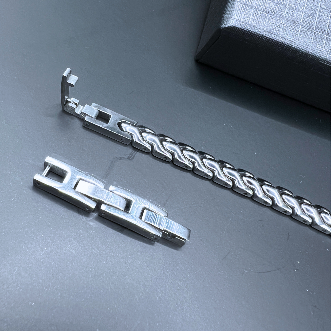 Close-up of the Aegon bracelet showing the detachable extension links and clasp mechanism on a black surface with the branded box in view.