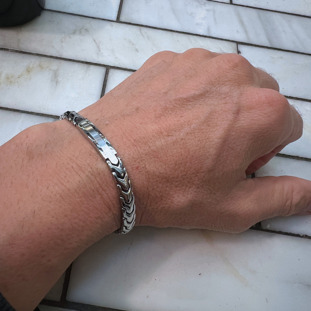 Aegon bracelet worn on wrist in natural outdoor lighting, highlighting the reflective polish and intricate chain design against a tiled surface.