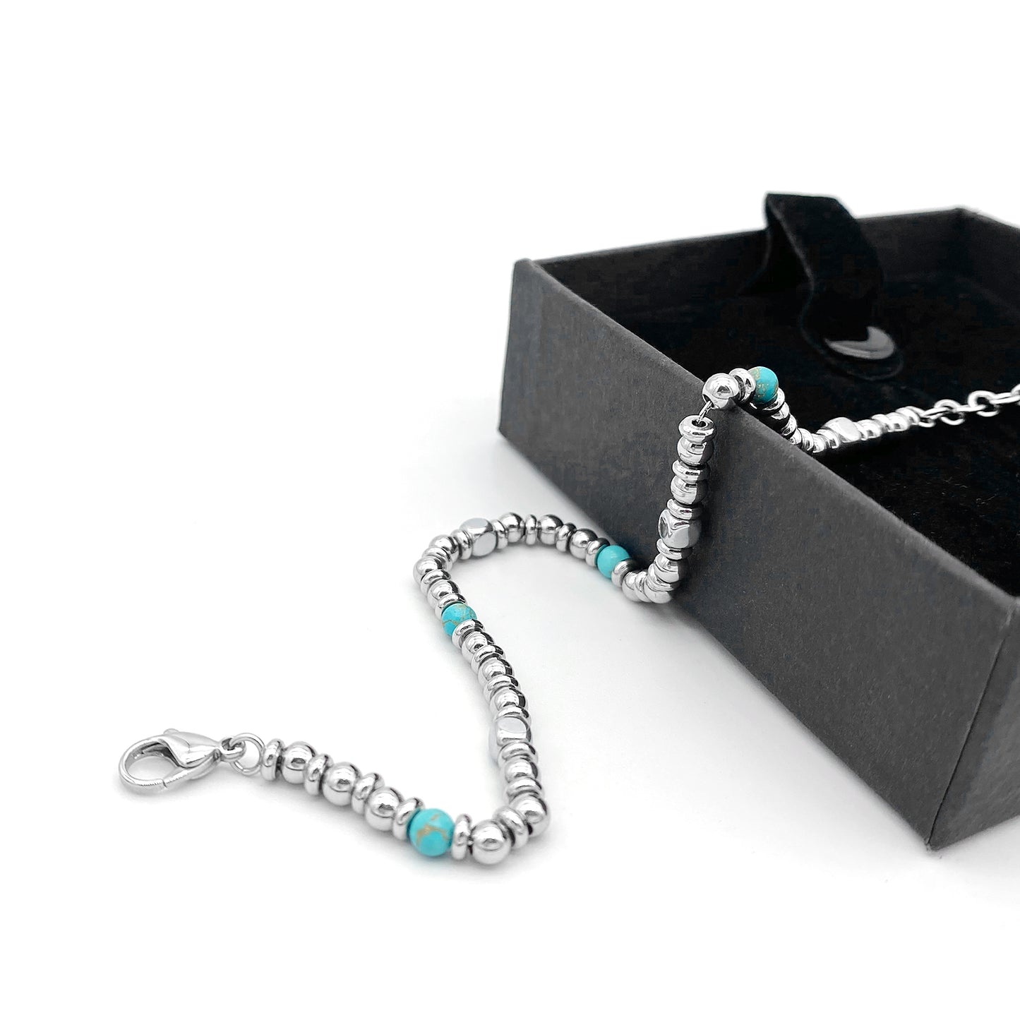 Aqua Pulse bracelet draped over a black box with turquoise and stainless beads, white background
