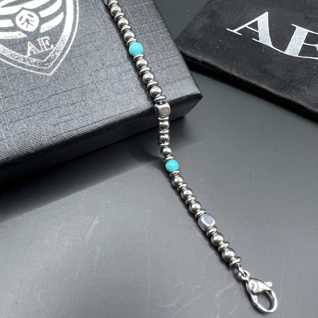 Aqua Pulse bracelet diagonally displayed with turquoise bead accents, Armoured Elegance box and pouch