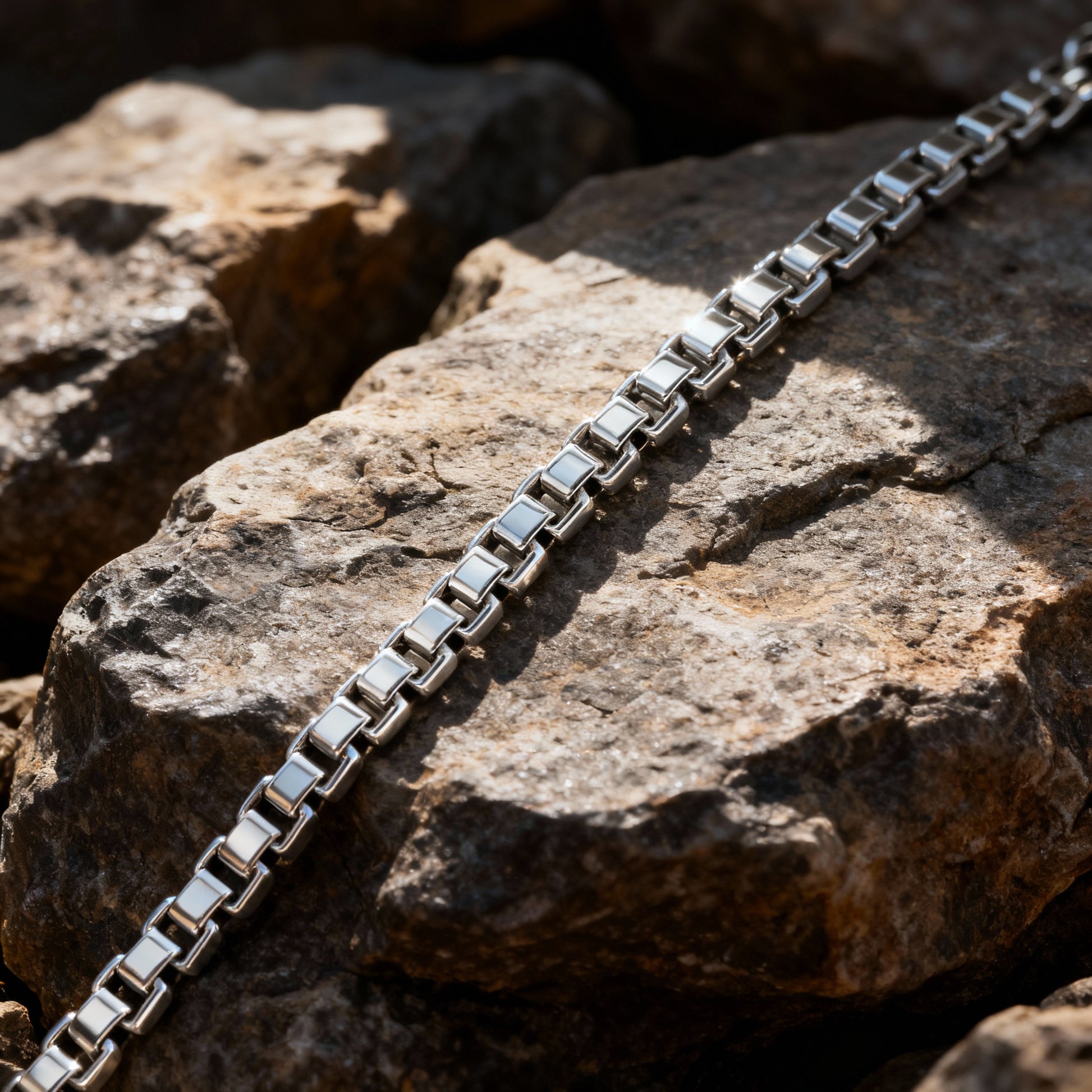 Close-up of the Element stainless steel box chain bracelet resting on natural rocks — premium men’s jewellery by Armoured Elegance.