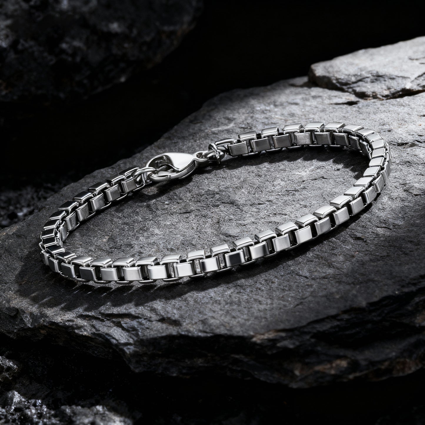 Element stainless steel box chain bracelet displayed on dark textured rocks — premium men’s chain bracelet by Armoured Elegance.