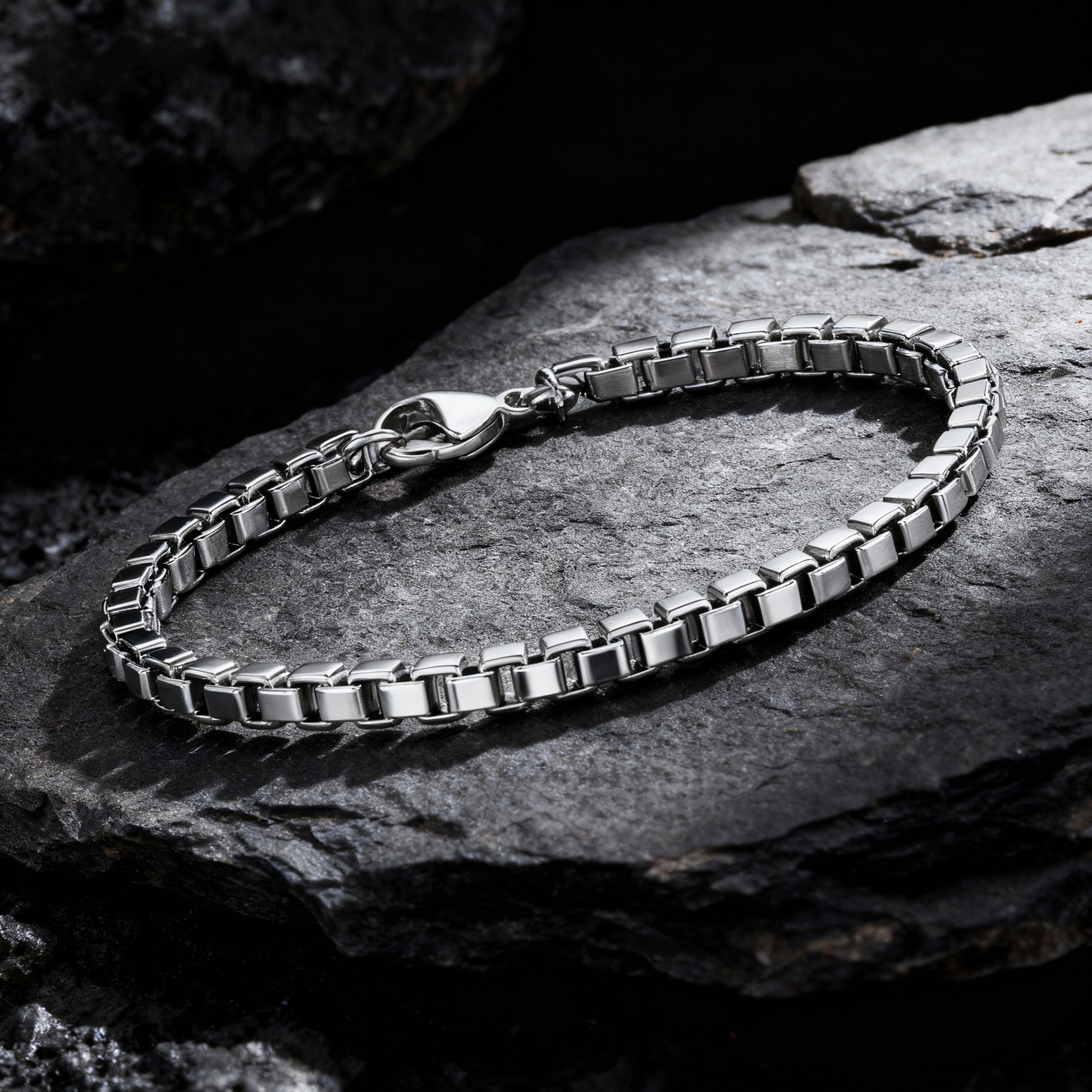 Element stainless steel box chain bracelet displayed on dark textured rocks — premium men’s chain bracelet by Armoured Elegance.