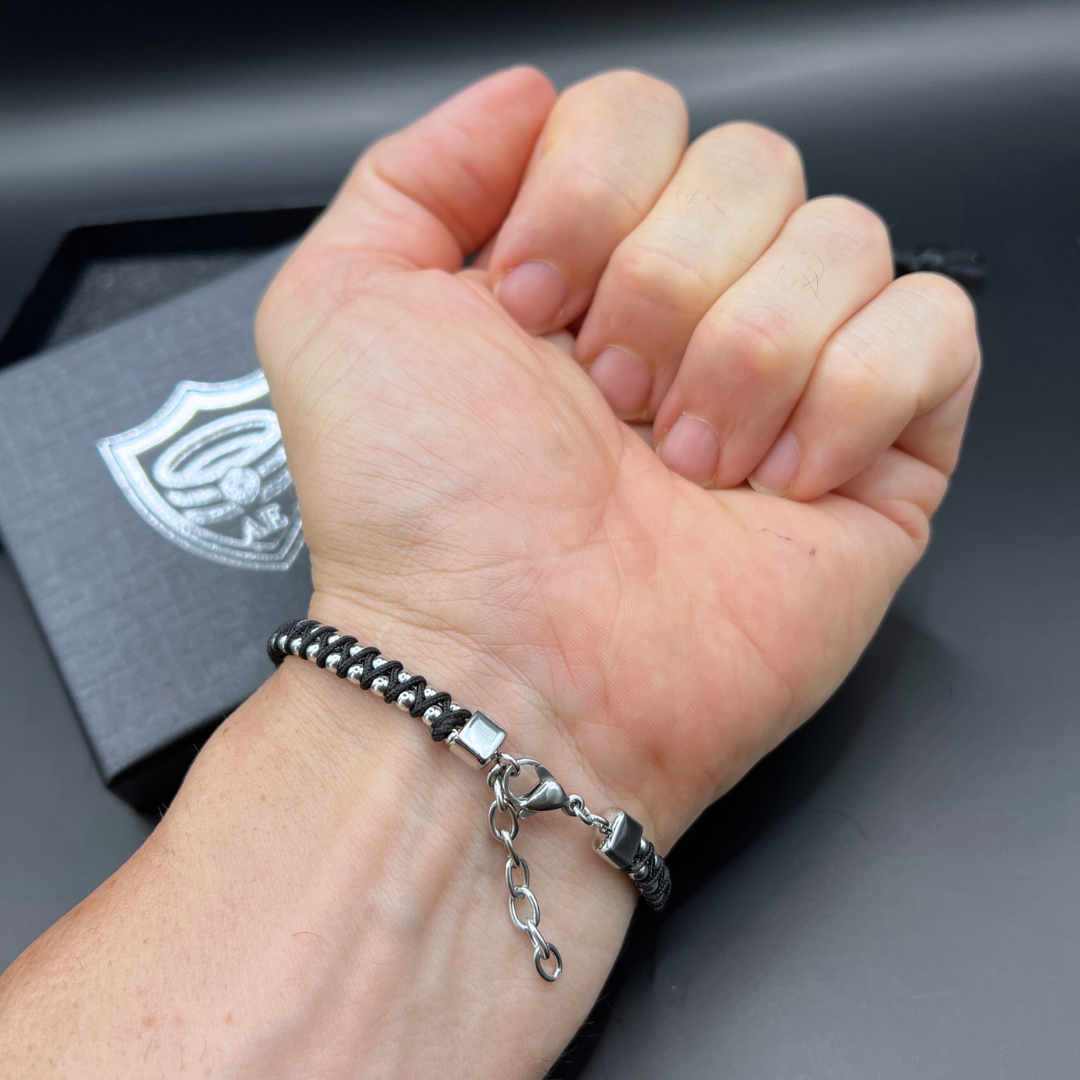 Adjustable black Synergy bracelet showing stainless steel lobster clasp and extension chain on wrist.