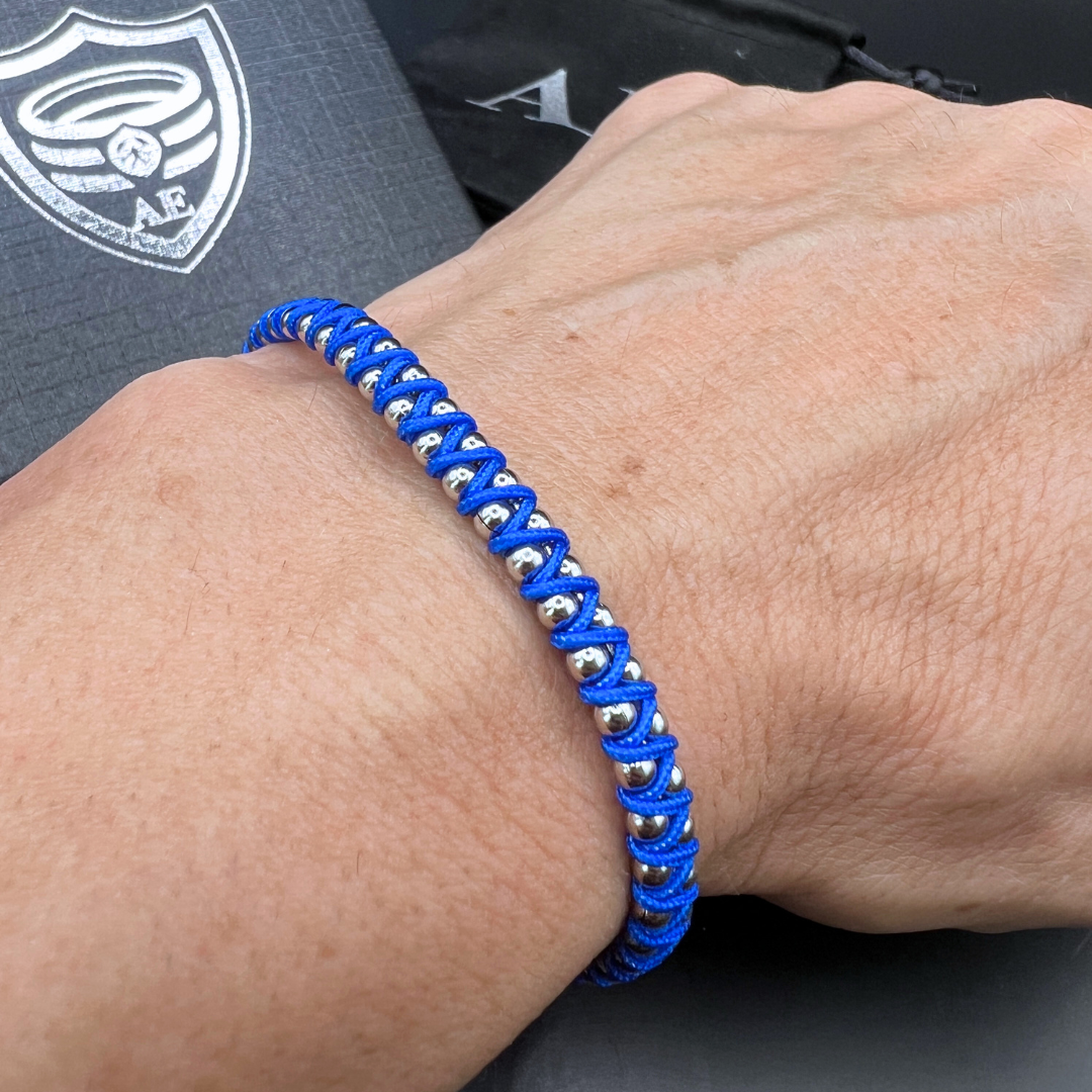 Blue Synergy bracelet with woven cord and stainless steel beads shown on wrist – casual masculine style.