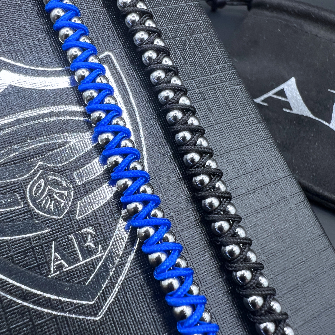 Close-up of blue and black Synergy bracelets showing woven cord design and stainless steel beads.