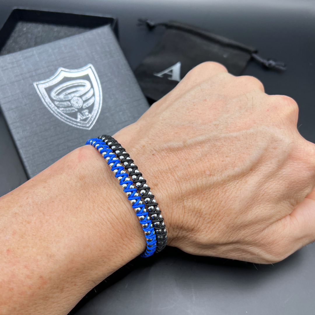 Armoured Elegance Synergy bracelets in blue and black worn together in a stacked wrist style.