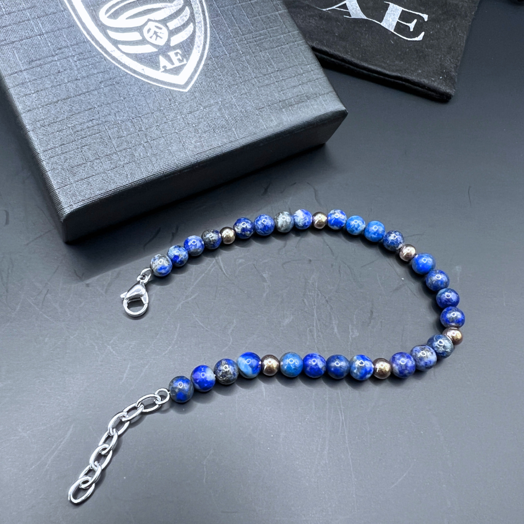 Auric Lineage Cosmic edition bead bracelet displayed flat on black surface with Armoured Elegance packaging.