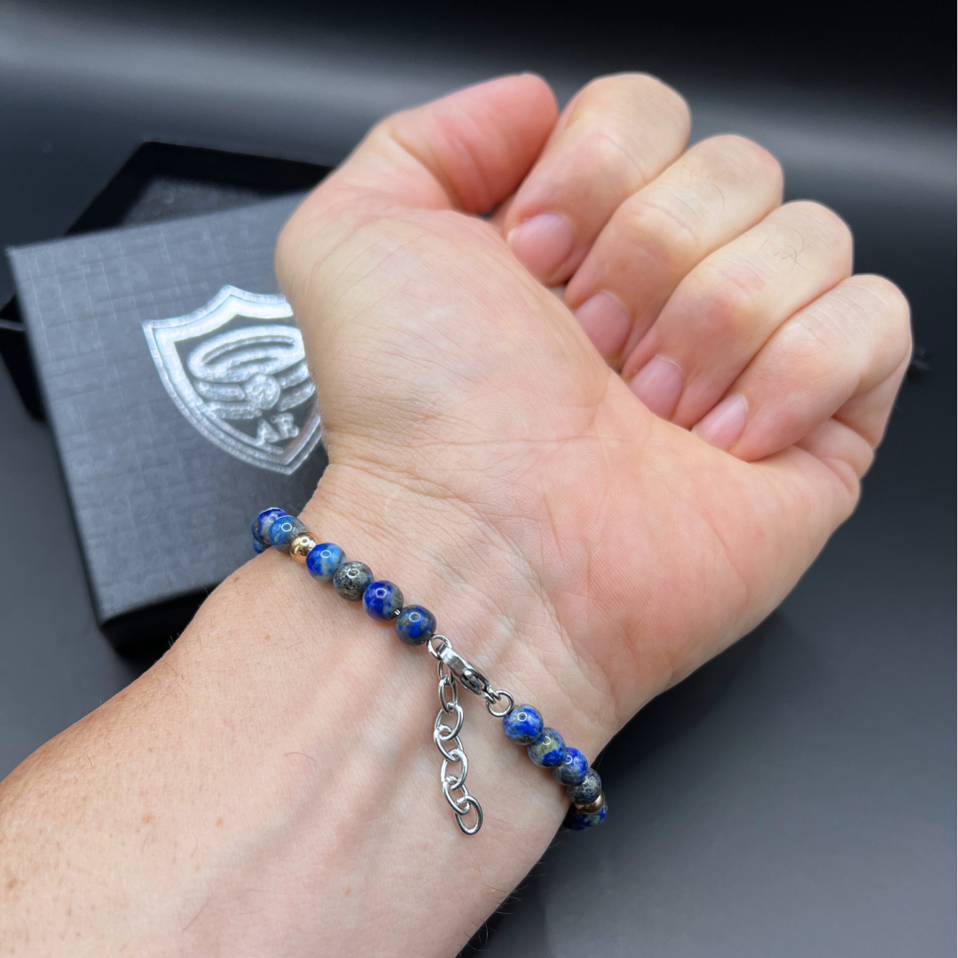 Auric Lineage Cosmic edition blue bead bracelet worn on wrist with gift box in background.