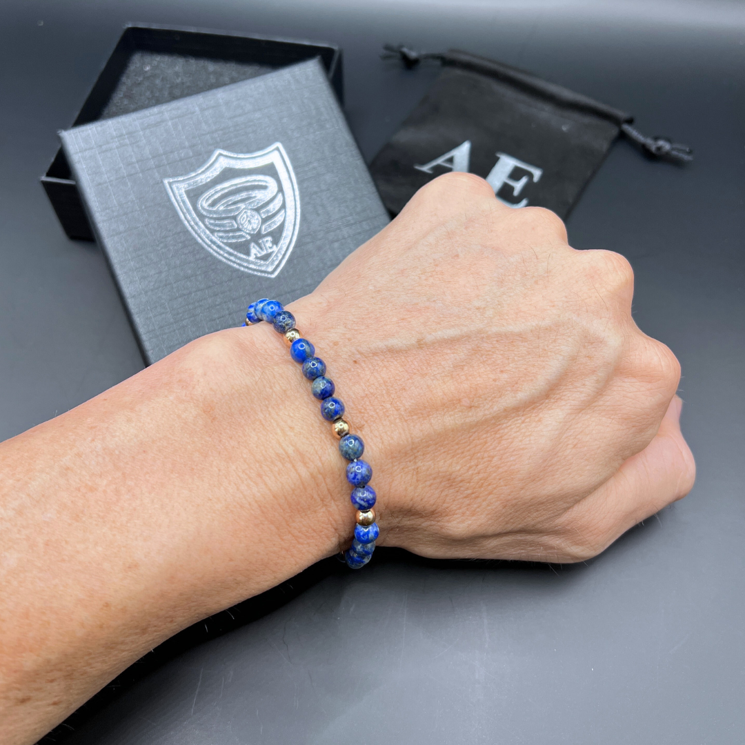 Auric Lineage Cosmic blue bead bracelet on wrist with Armoured Elegance gift box and pouch.