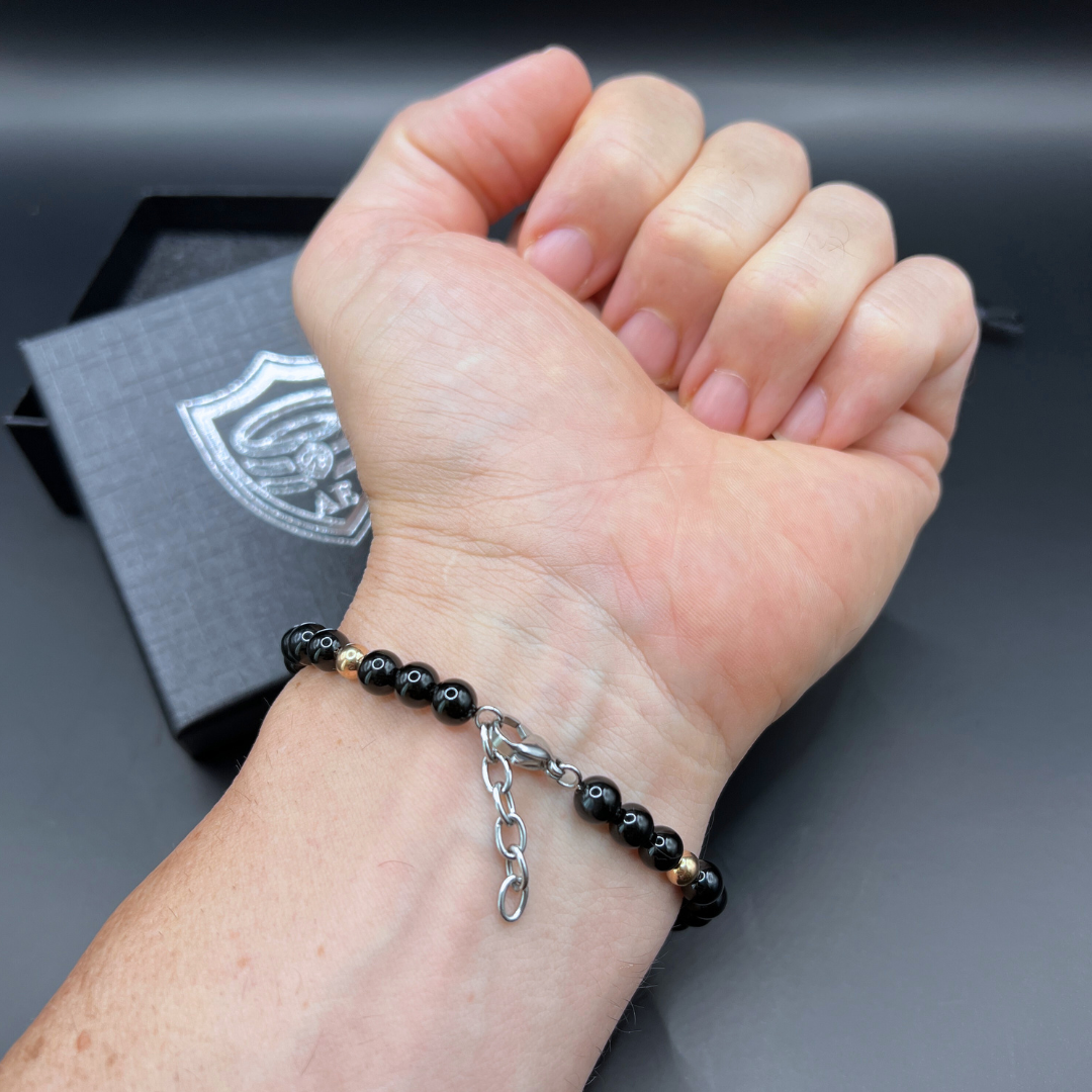 Close-up of Auric Lineage Shadow edition black bead bracelet worn on wrist with adjustable chain.