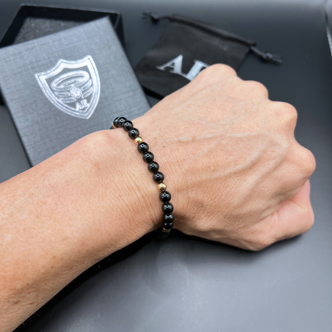 Auric Lineage Shadow edition black bead bracelet worn on the wrist showing gold accents.