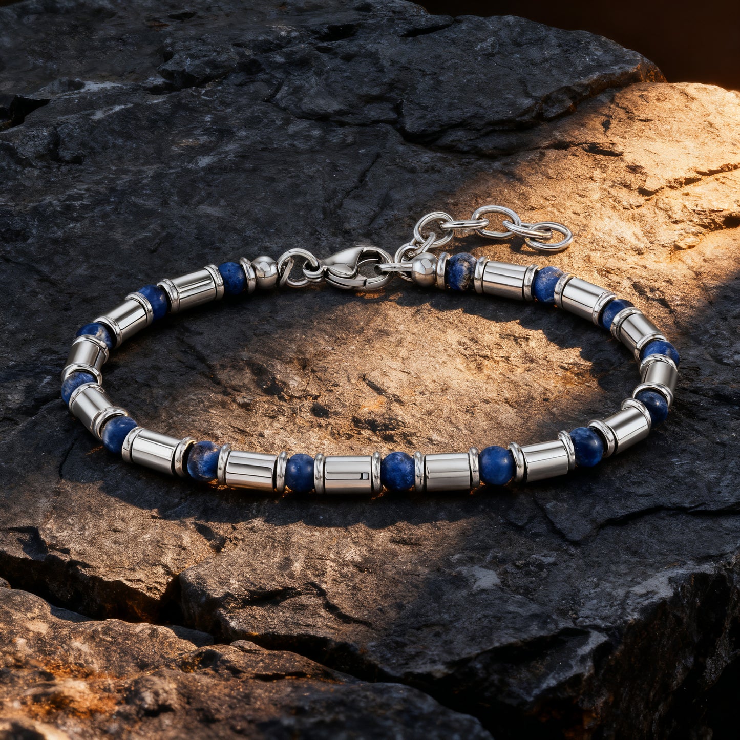 Earth Pulse bracelet with blue natural stones and stainless-steel tubes illuminated under warm light on dark textured rock.