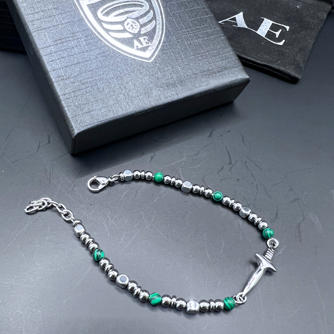 Legion bracelet laid flat showing malachite beads, stainless steel detailing, and sword centerpiece.