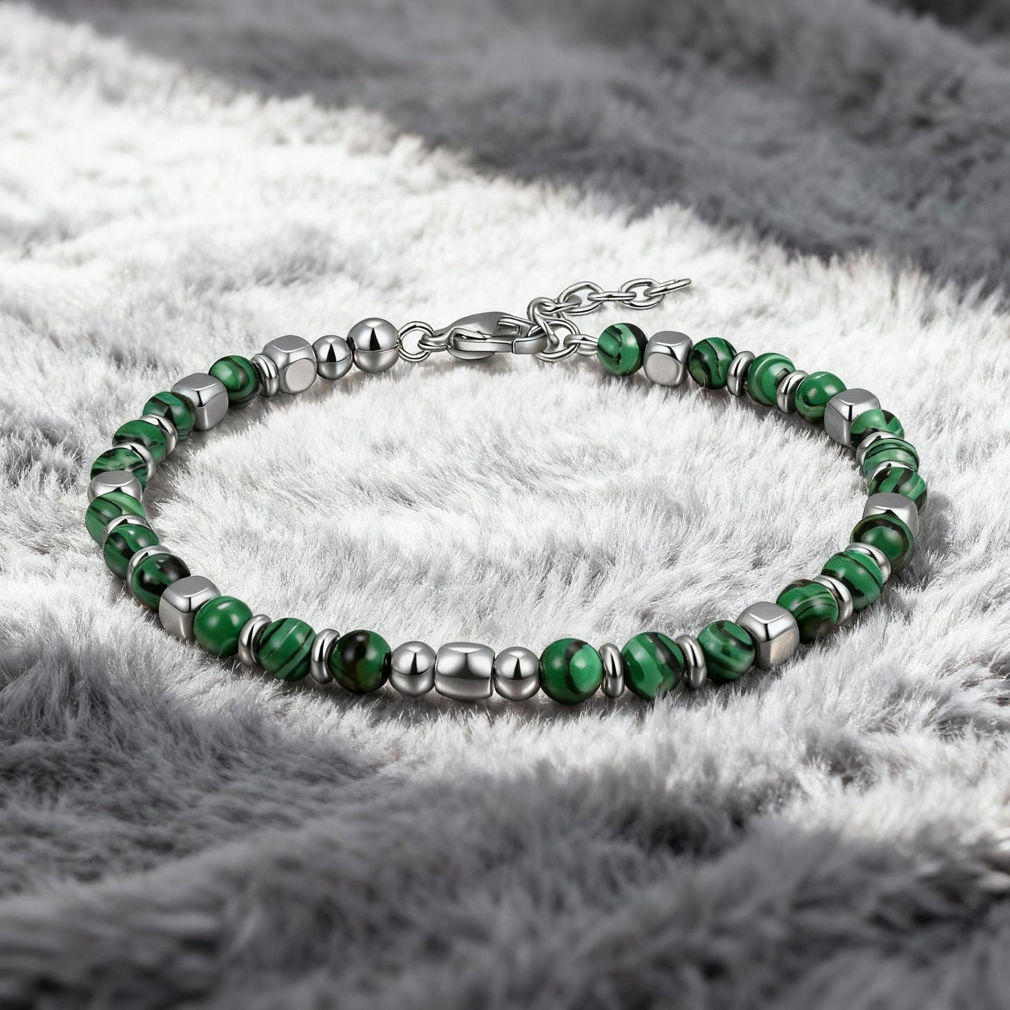 Luxury men’s Malachite Luxe bracelet featuring polished green malachite stones and stainless-steel beads displayed on soft grey fabric background.