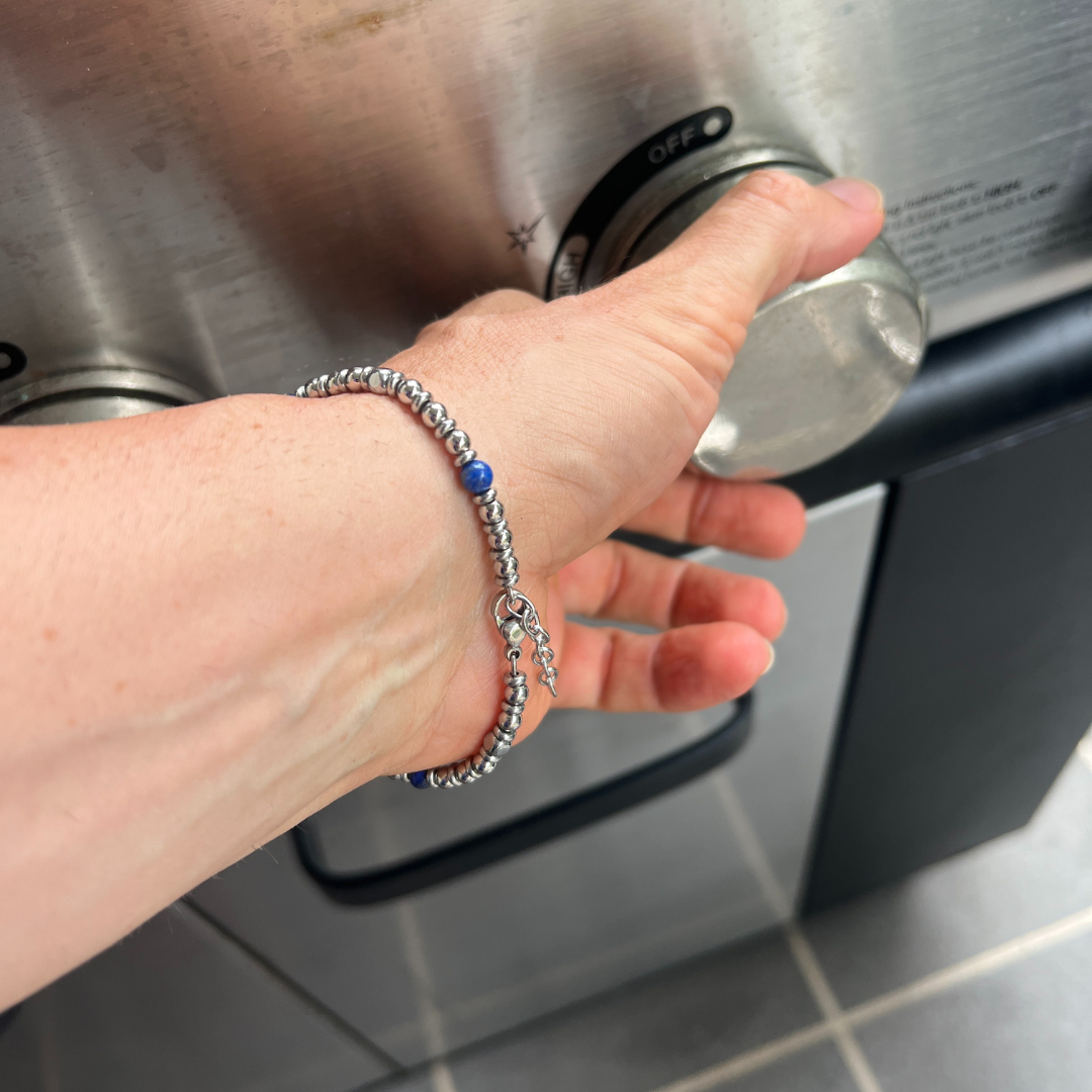 Midnight Pulse bracelet worn on wrist while turning a stainless steel appliance knob