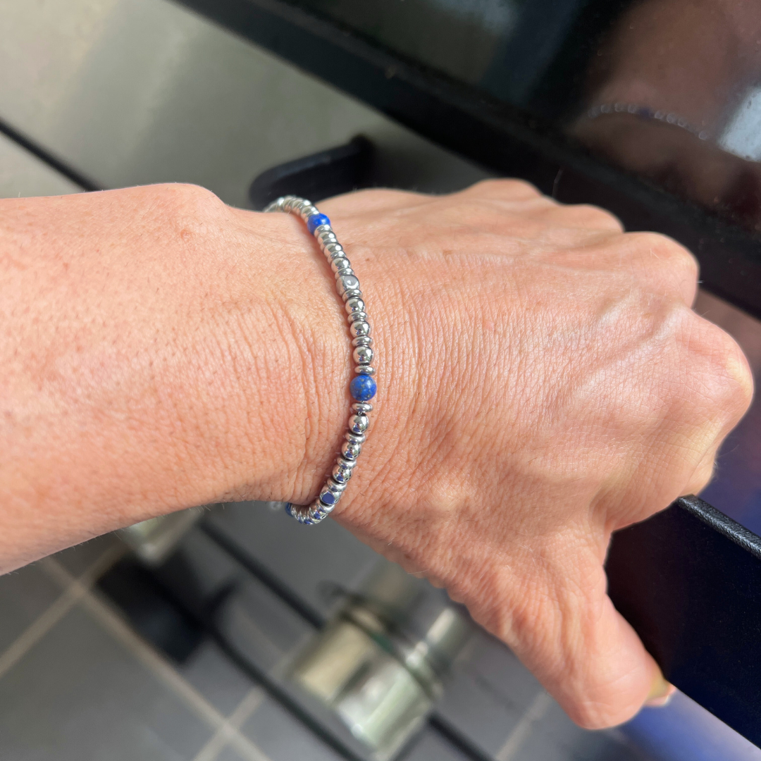 Top view of Midnight Pulse bracelet styled on wrist with blue stones and polished steel beads