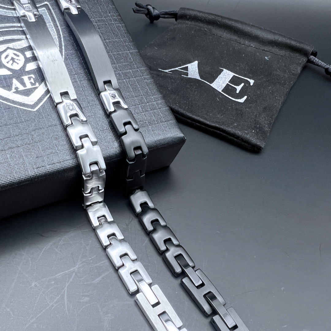 Black and silver Sentinel bracelet links shown side by side beside Armoured Elegance gift box.