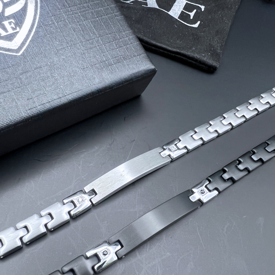 Shadow Sentinel black bracelet and Steel Sentinel silver bracelet displayed together beside Armoured Elegance box.