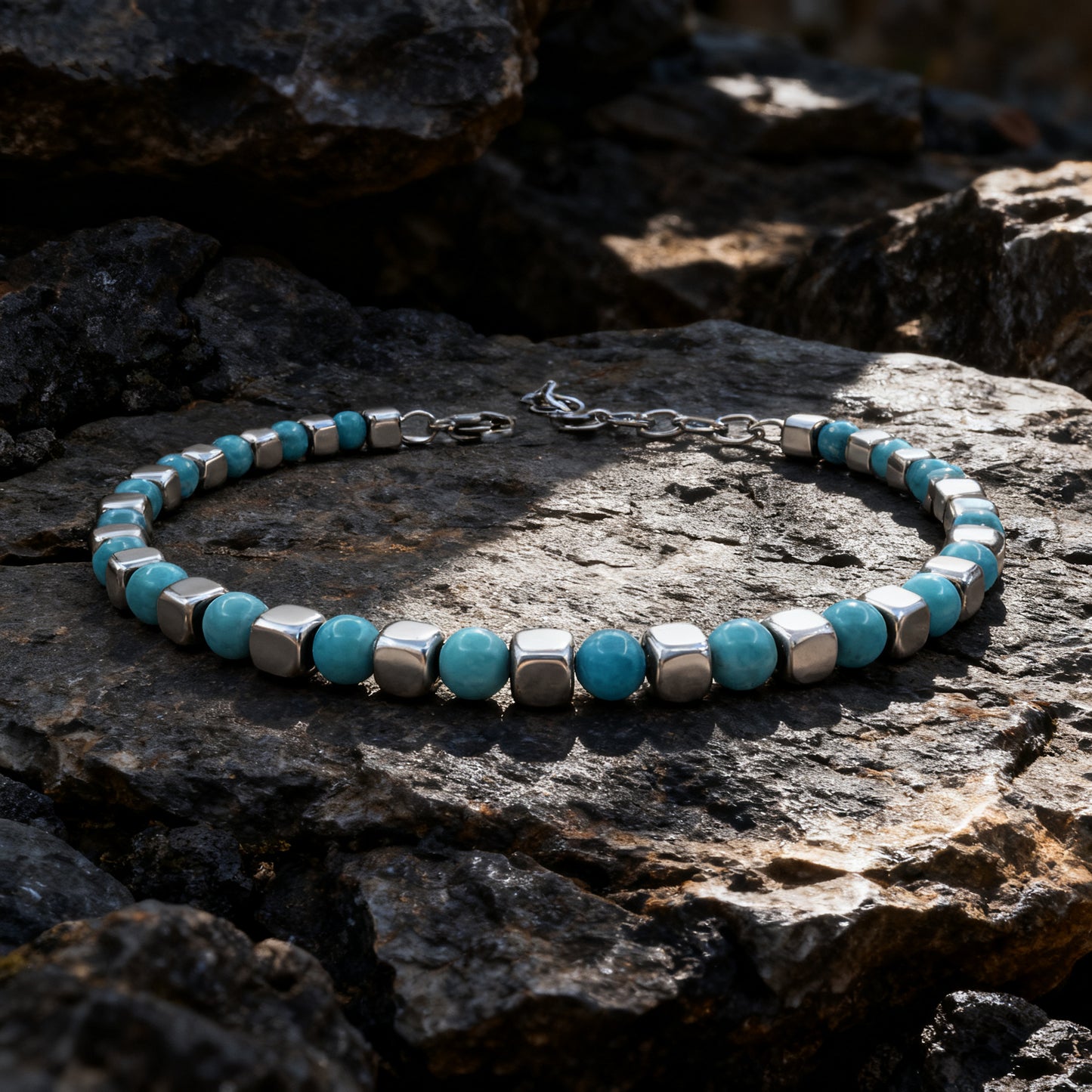 Turquoise Rhythm bracelet photographed on natural rock surface under sunlight, emphasizing contrast between turquoise stones and polished stainless steel.