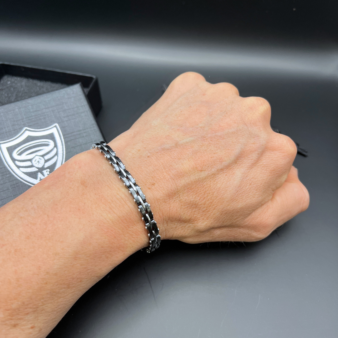 Front view of the Velocity Steel Surge bracelet styled on wrist with Armoured Elegance packaging.