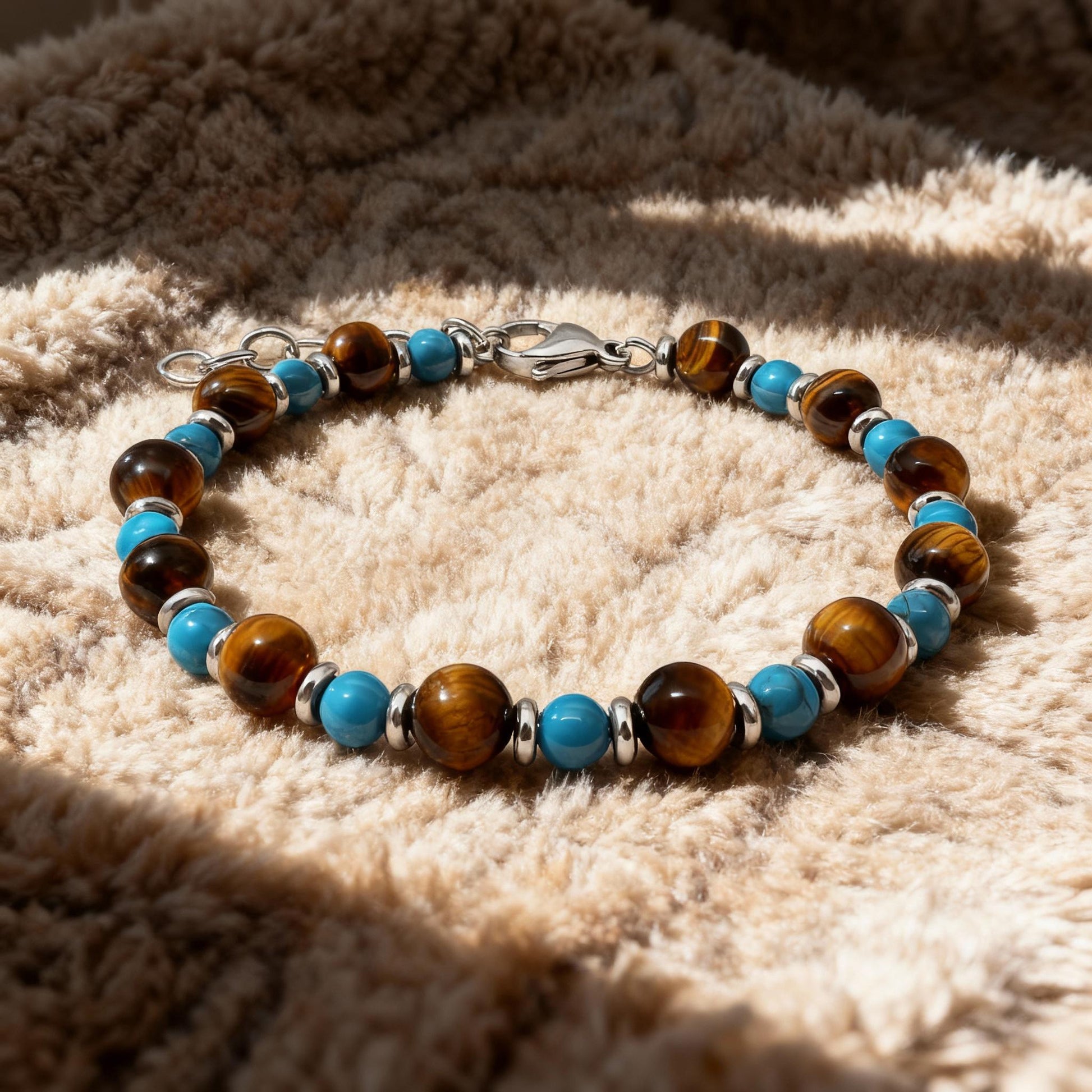 Wild Oasis bracelet with turquoise and tiger eye natural stones resting on soft beige fabric, highlighting its warm tones and polished finish.